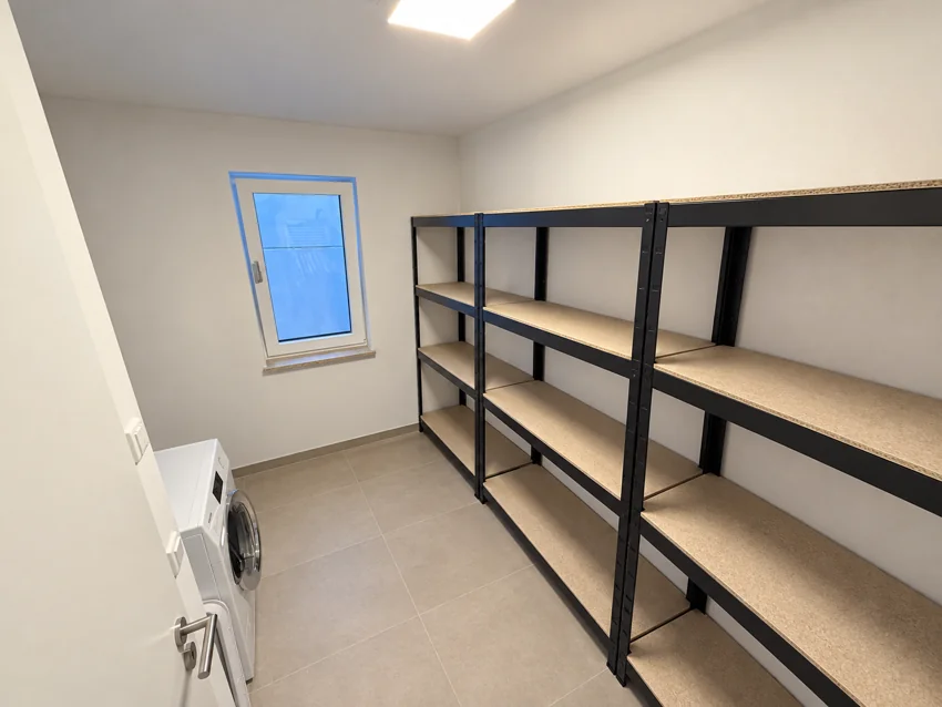 Storage and utility room with a Miele washer-dryer and empty shelving