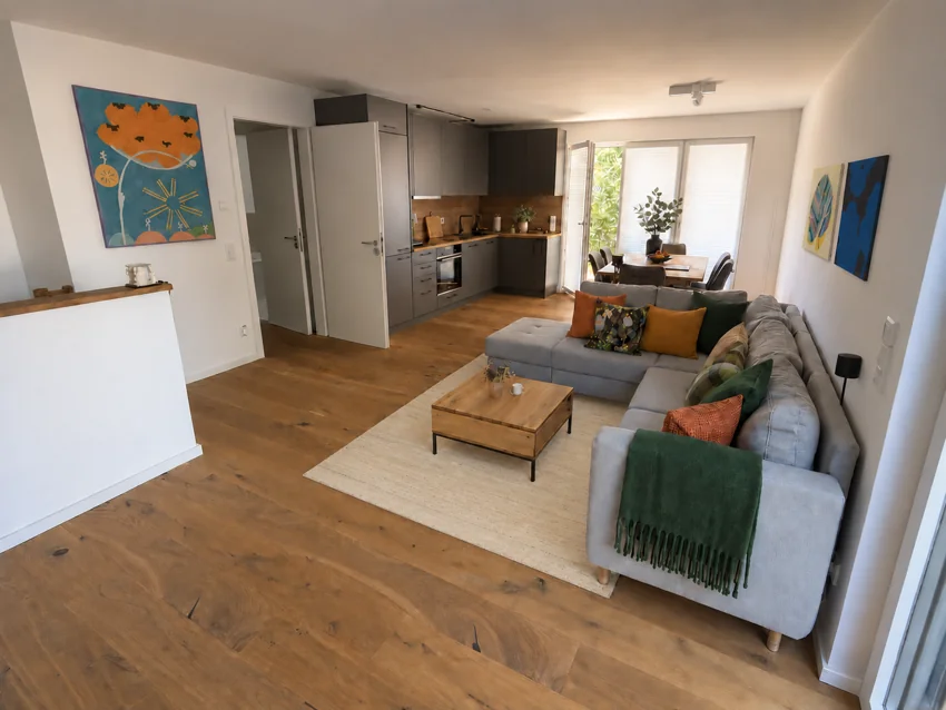 Living area with an open kitchen, sofa and dining space by the window